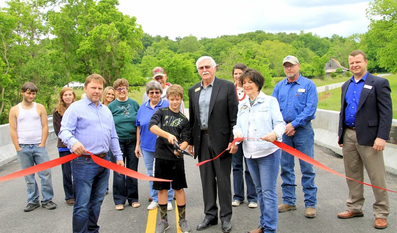 Photo by Steve Huckriede Young River Soule&#8217; cut the ribbon to officially open the new Stage Coach Bridge in ceremonies last Thursday afternoon. Stage Coach Road has been closed to traffic during construction of the new bridge spanning Spavinaw Creek. Kurt Maddox, mayor of Gravette, stands to River&#8217;s left and to his right are Bob Clinard, Benton County Judge, and Mary Lou Slinkard, Arkansas state representative. Several area residents and Benton County road department employees were on hand for the ribbon cutting.