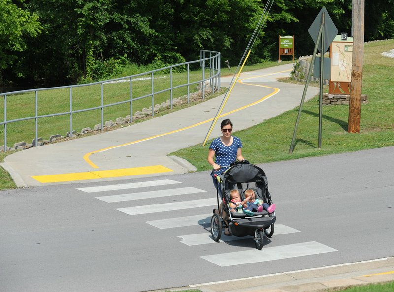 Lauresa Larson of Bentonville walks Tuesday across Southeast Riviera Road with her 18-month-old twin daughters Peyton (left) and Zoe while on their way to Horsebarn Trailhead Park along the Razorback Greenway in Bentonville.