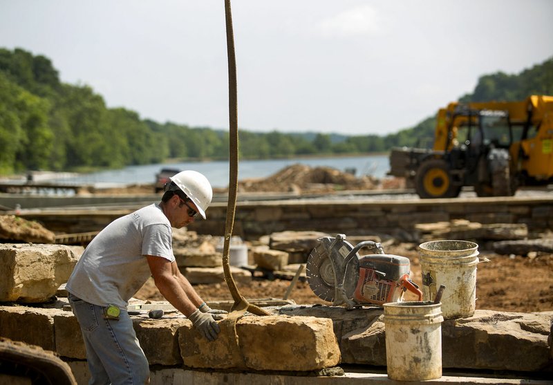 Eric Wills with Hammer & Chisel works on a rock wall Tuesday at Lake Atalanta in Rogers.