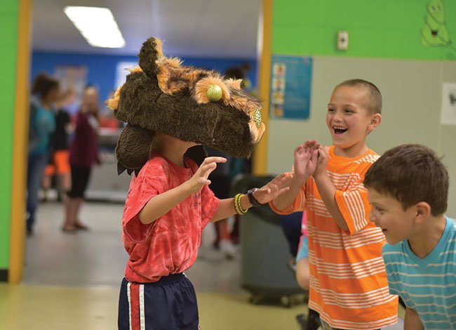 Kindergartner Howard Wade, left, scares classmates Tristan Wallingsford, center, and Jesus Santos during a session on crafting puppets at the Experiencing the Arts Field Day at White County Central Elementary School in Judsonia.