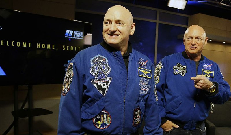 Retired NASA astronaut Scott Kelly, left, and his twin Mark get together before a press conference Friday, March 4, 2016, in Houston. 