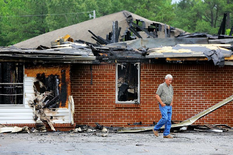 Phillip Roark walks away from a burned classroom area Wednesday outside Poyen Missionary Baptist Church, which was damaged in a fire Tuesday evening. No injuries were reported, but the Poyen church’s sanctuary, offices and classrooms were ruined. More photos are available at arkansasonline.com/galleries. 