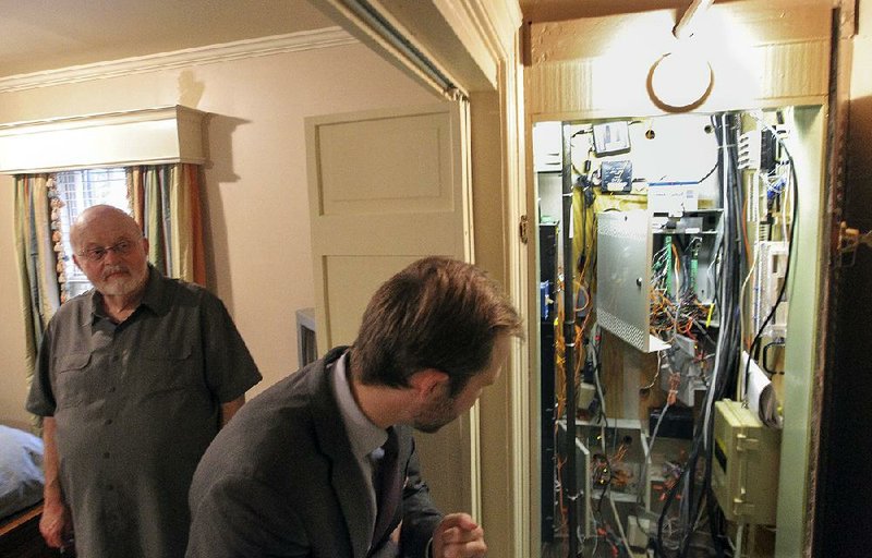 Don Bingham (left), mansion administrator, and J.R. Davis, spokesman for Gov. Asa Hutchinson, show loose wiring from a former security system in the closet of the Governor’s Mansion guesthouse while giving a tour of some of the problems affecting the mansion and other buildings on the grounds.