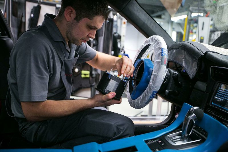 An employee prepares an air-bag unit for a Porsche 911 at Porsche AG’s factory in Stuttgart, Germany, in this file photo. Recalls for 12 million more vehicles to replace potentially faulty air-bag inflators made by Takata Corp. were announced Friday. 