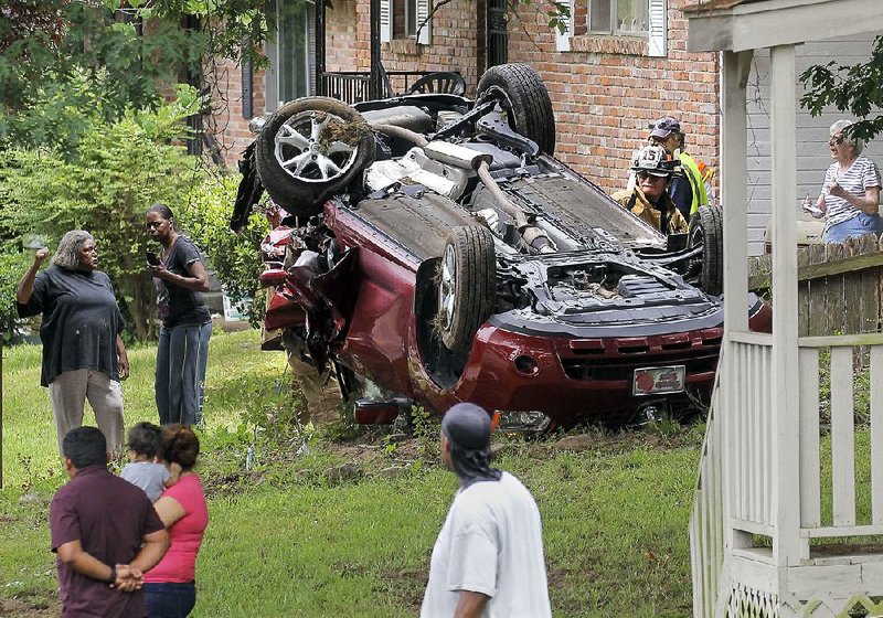 Neighborhood residents gather near an accident scene at 36th and Potter streets in Little Rock. Four people were taken to a hospital after the accident, which involved five cars, authorities said. 