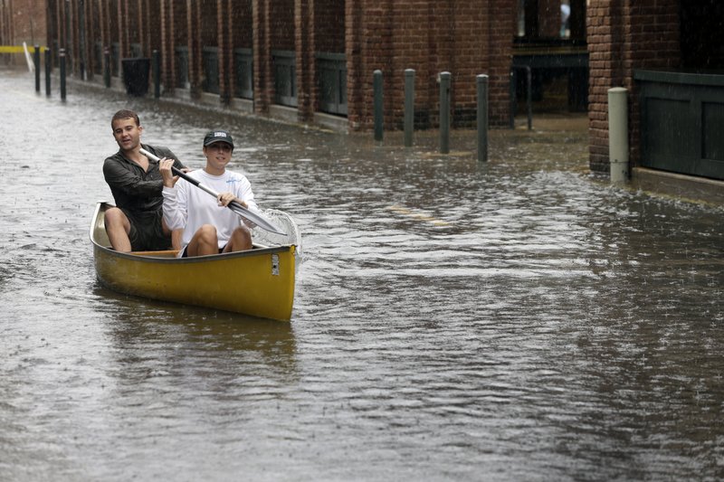 In this Oct. 3, 2015 file photo, Dillon Christ, front, and Kyle Barnell paddle their canoe down a flooded street in Charleston, S.C. 
