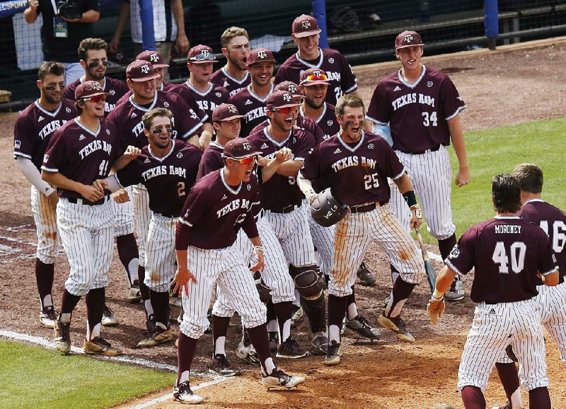 Texas A&M’s Walker Pennington (lower right) is welcomed by teammates after hitting a three-run home run Saturday in the eighth inning of the Aggies’ 12-8 victory over Mississippi at the SEC Tournament in Hoover, Ala. The Aggies scored seven runs in the game’s final two innings to advance to today’s championship game against Florida.