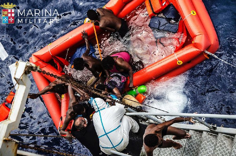 Rescuers help migrants board the Italian navy ship Vega after the boat they were on sank Friday in the Mediterranean Sea. The Italian navy said it rescued 135 migrants and recovered 45 bodies from the sea. 
