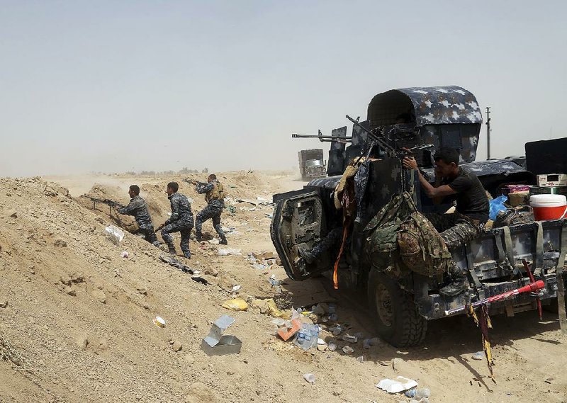 Iraqi police fight Islamic State militants Saturday outside Fallujah, Iraq. Islamic State forces were also battling Syrian rebels Saturday after entering Marea, an opposition stronghold. 