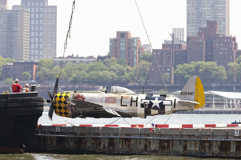 Workers lift the plane that was pulled Saturday from the Hudson River onto the pier of the Downtown Manhattan Heliport, also known as the Wall Street Heliport, in New York City. 