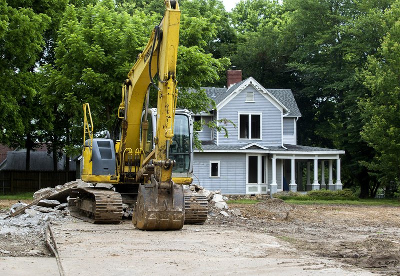 An excavator rests Friday on the property at 701 W. Central Ave. in downtown Bentonville. The house at 703 W. Central Ave. (in background) is the subject of a plan move it to a new location.