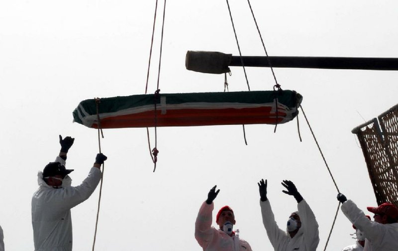 Workers on Sunday at the harbor in Reggio Calabria, Italy, transport one of 45 bodies found in the Mediterranean Sea after a boat filled with migrants capsized.