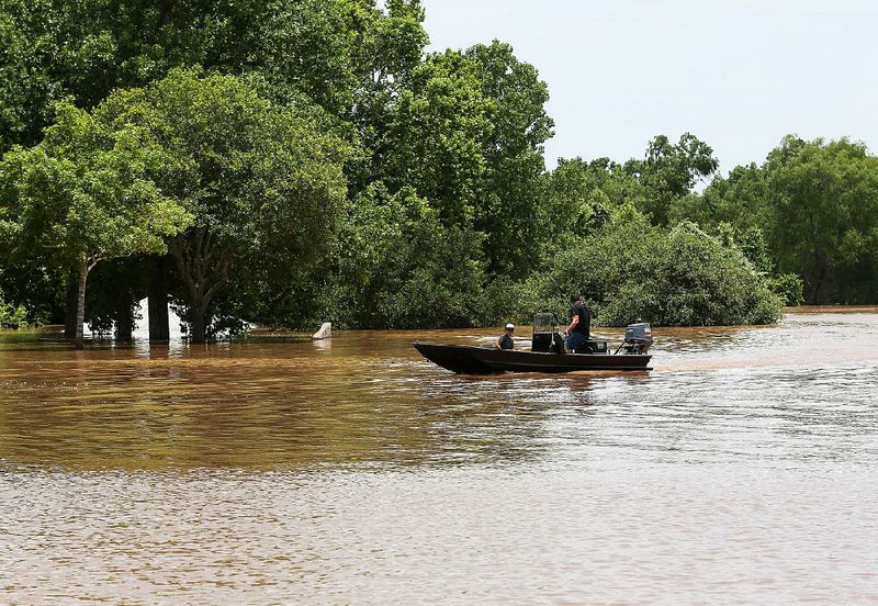 Two people pilot a boat on the flooded Brazos River on Sunday in Rosenberg, Texas.