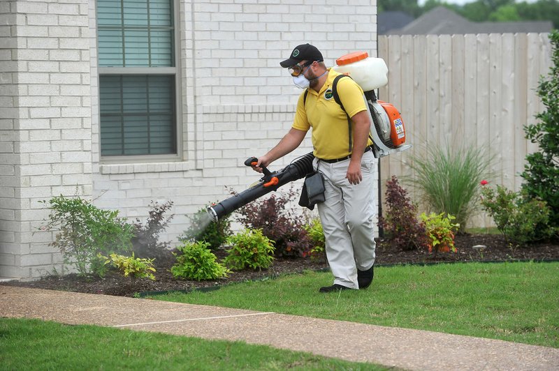 Dakota Ross, Territory Manager for the Northwest Arkansas region of Mosquito Joe, sprays a home for mosquitoes Friday in Fayetteville.