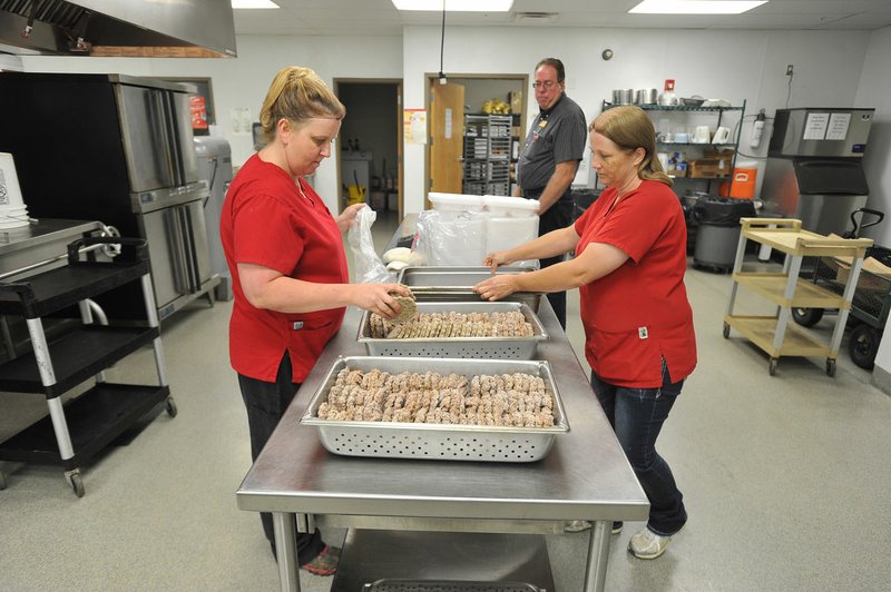 Kim Bartlett (from left), Danny Beard, child nutrition director, and Tammy Wilson prepare lunch Friday at the West Fork Elementary School cafeteria. 