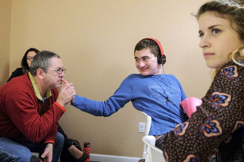Gordy Baylinson, who has autism and is nonverbal, reaches back to caress the face of his father, Evan Baylinson, during a therapy session with Meghann Parkinson (right) at Growing Kids Therapy Center in Herndon, Va. 
