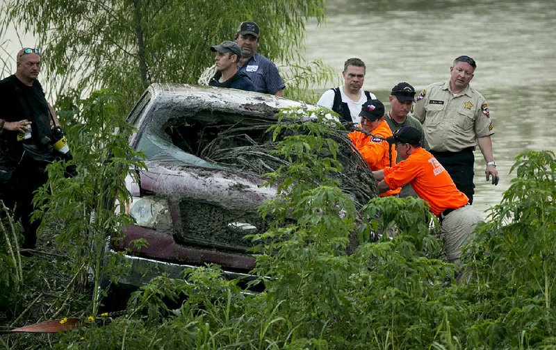 Responders with Texas Search and Rescue on Tuesday look inside a truck that was swept away in a flood and found in a pond in Austin.