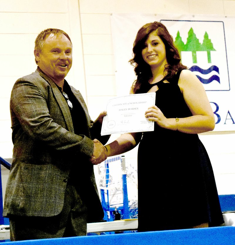 Photo by Mike Eckels Haley Burden (right) receives a $36,000 scholarship from Toby Conrad, high school principal, during the 2016 Decatur High School Scholarship awards presentation May 9 at Peterson Gym in Decatur. The full scholarship Burden received is from Arkansas Tech University in Russleville.