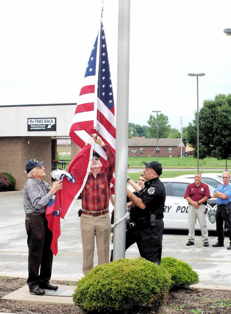 Photo by Randy Moll A flag-raising ceremony was held Friday at the new Gentry Police Station. Assisting officer Rick Lane, a Navy veteran, were two other Navy veterans, Robert Meyer and Burl Lyons. Meyer served from 1947 to 1952 and Lyons served from 1952 to 1974.