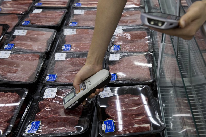 In this Monday, Nov. 9, 2015, photo, a worker measures the temperature of Australian beef on display at a Sam's Club in Shenzhen, China. Over the past two years, Sam's Club has changed the way it sells meat and fish, by putting them in packages, instead of letting customers physically inspect the products. 