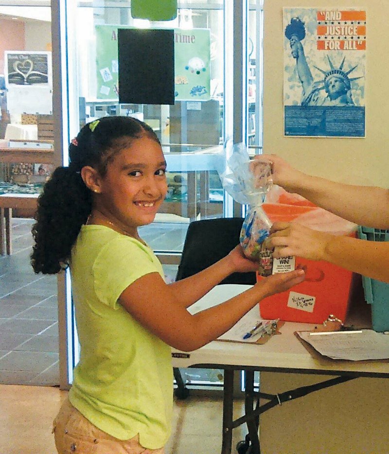 Ariana Gonzalez, 8, receives a Food for Good meal at the Esther DeWitt Nixon Library in Jacksonville. From now until the first day of school, the library will provide free lunches at noon each weekday to youth ages 3 to 18.