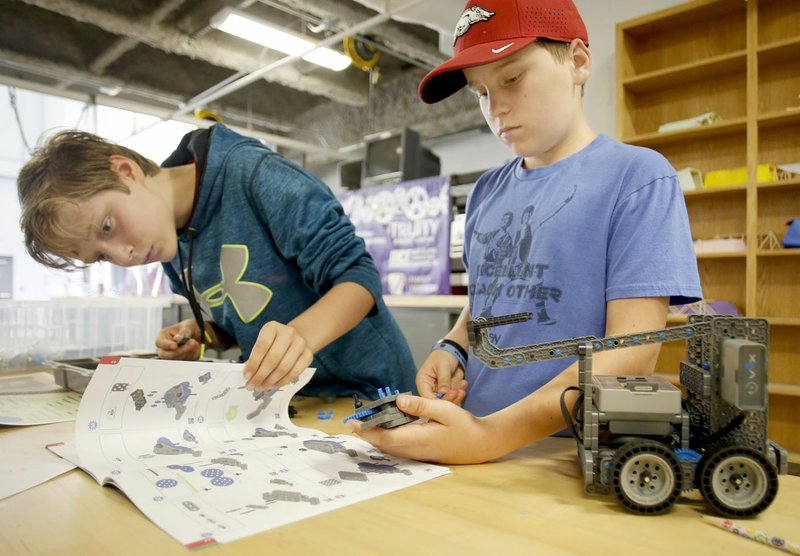 Kele Estes-Beard (left), 12, looks over the diagrams as Baydon Fuller, 13, collects parts for assembly Wednesday as they participate in the Fayetteville Robotics Summer Camp at Fayetteville High School. The four day class uses the Vex IQ Robot platform.