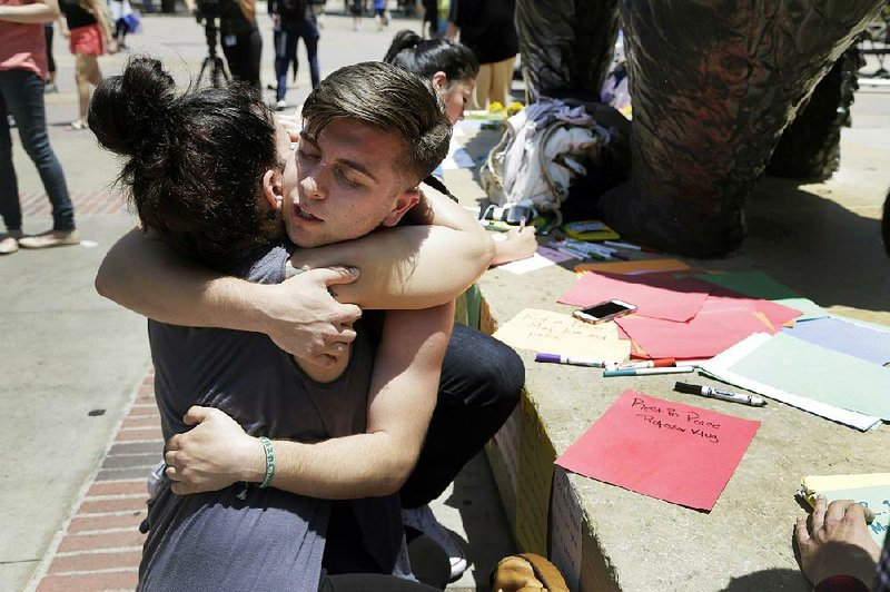 University of California, Los Angeles students Stephany Drotman and Joseph Perez embrace after leaving notes of condolence for shooting victims Thursday at the foot of the Bruin Bear statue.