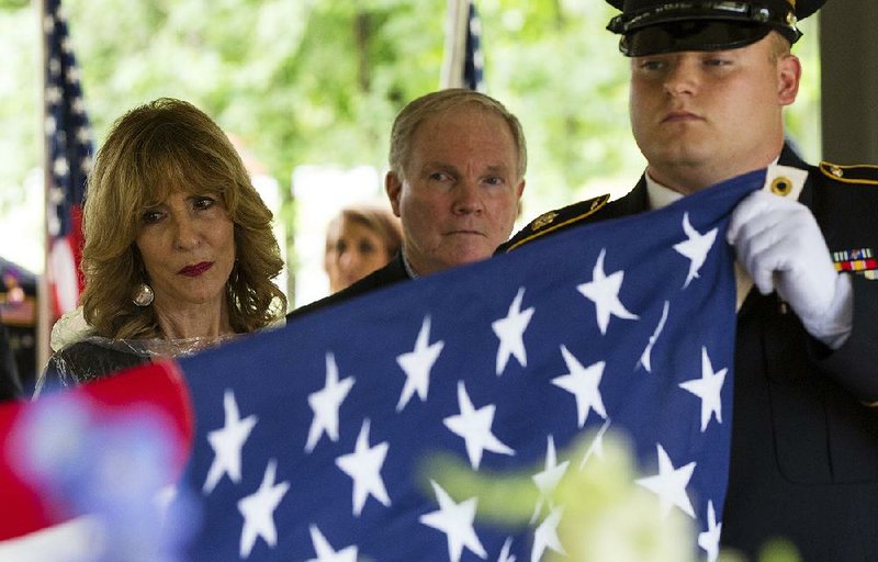 Lynne Reina Tobias, the aunt of U.S. Army veteran William Reina, and his uncle Bob Tobias watch as an American flag is folded by Staff Sgt. Jacob Thurber during a memorial service Friday for Reina at the Arkansas State Veterans Cemetery in North Little Rock.