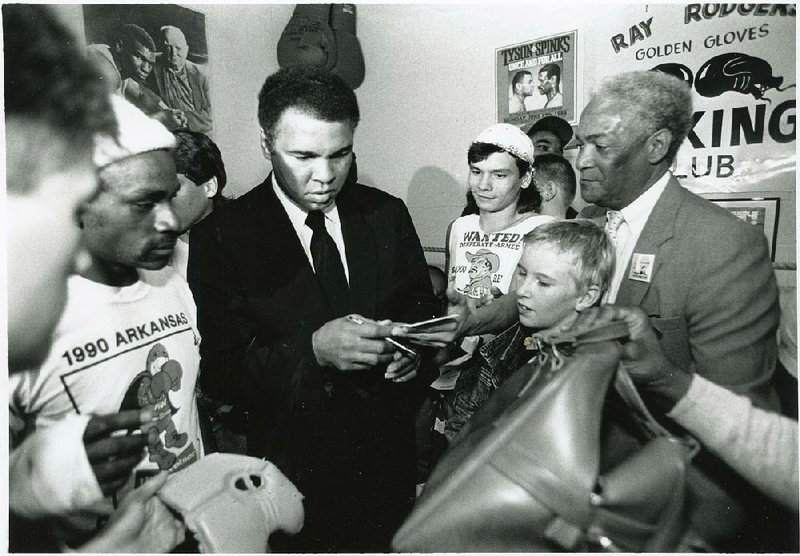 Former heavyweight champion Muhammad Ali (center) signs autographs for fans during a visit to Ray Rodgers’ boxing club in Little Rock on Nov. 8, 1990. 