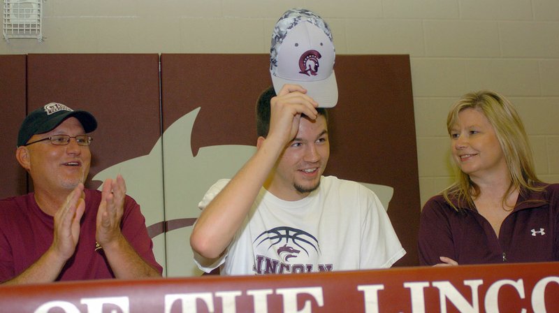 Shandon Goldman puts on an Arkansas-Little Rock cap after signing a basketball scholarship with the Trojans during a ceremony at Lincoln High's gymnasium on Saturday, June 4, 2016. Goldman, who attended prep school after graduating from LHS in 2015, is flanked by his father, Greg Goldman, and mother, Alicia Goldman.