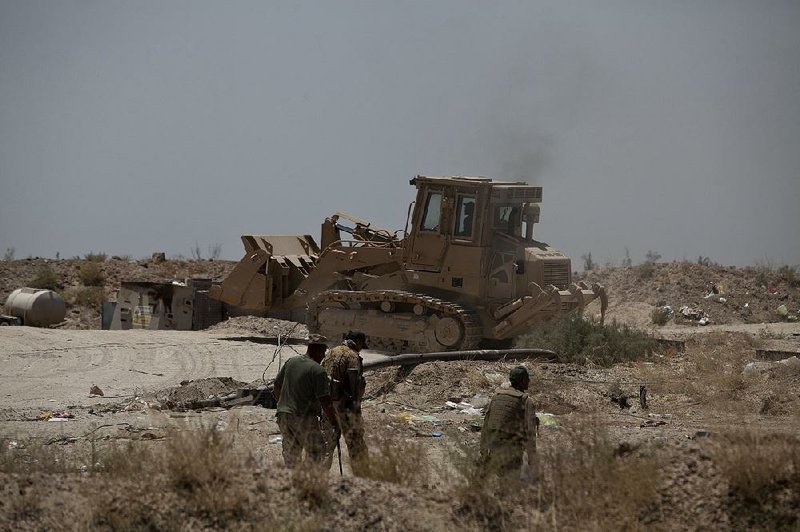 An Iraqi counterterrorism soldier drives a mine-resistant bulldozer as Iraqi army troops patrol the front line Tuesday as forces continue an offensive to oust the Islamic State from Fallujah.