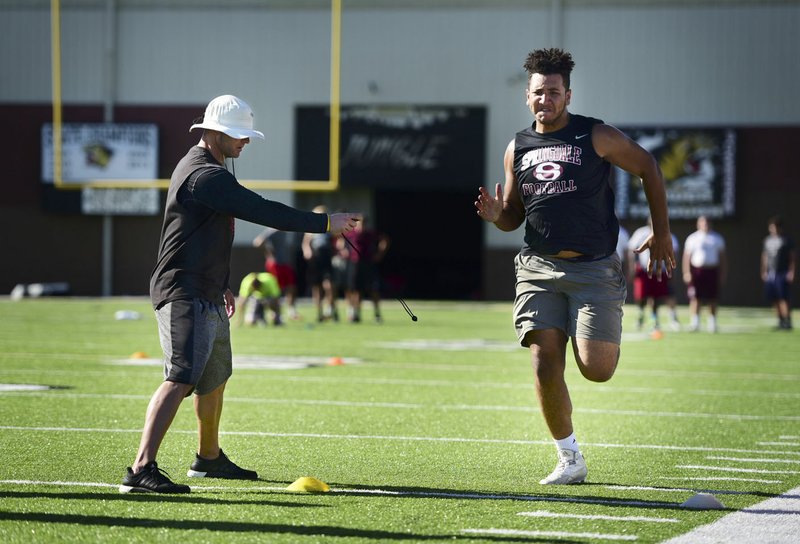Brian Early, left, an assistant coach with Arkansas State, times Isaiah Nichols of Springdale in the 40-yard dash Tuesday on the Bentonville High football field.