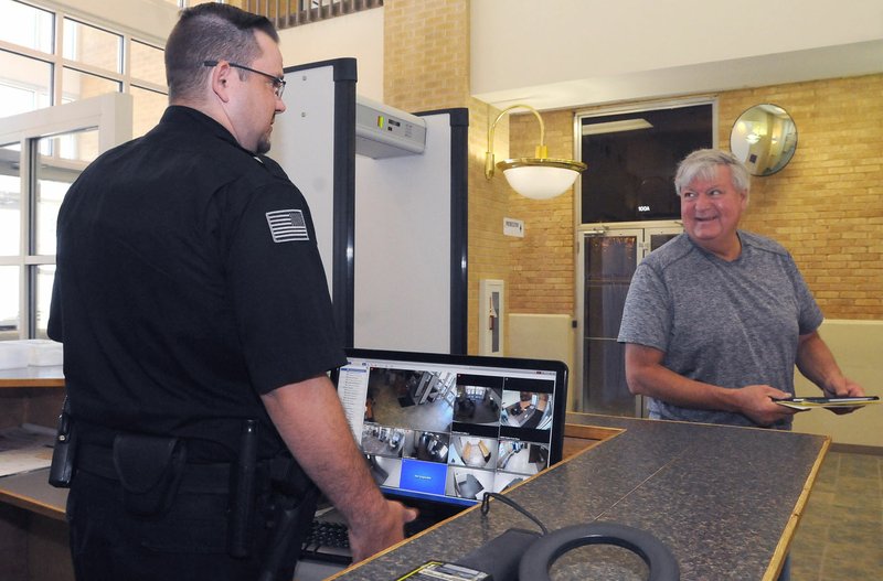 Deputy Joshua Pierson (left) chats Tuesday with Floyd Reed after Reed went through a courthouse security check in Bentonville.
