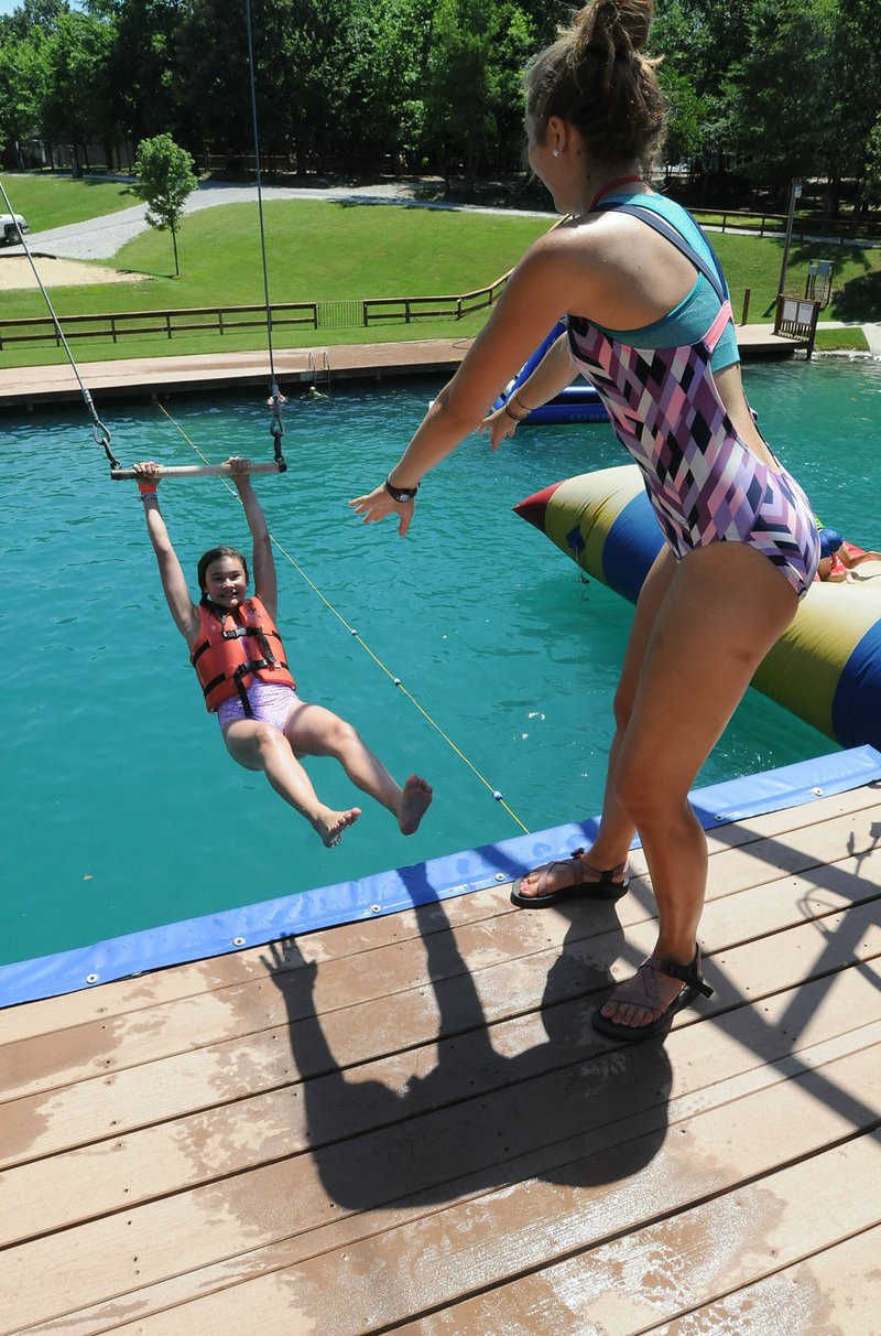 Halle Hill (left), a camper at Camp War Eagle, is set Wednesday to take a pool plunge from a swing with help from Jordan Maass, a counselor at the camp near Rogers.