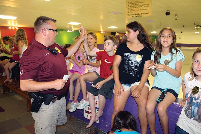 Officer Bobby Shell hands out Benton Police Department stickers at the Benton Skate Center to children from A Kids Place day care.