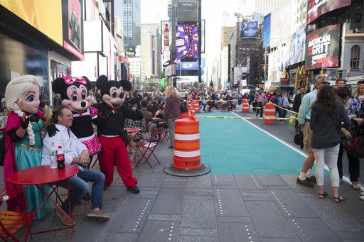 A visitor to New York's Times Square poses for a photo with costumed characters next to an area that is being prepared as a color-coded Designated Activity Zone on Thursday. The city has started painting teal rectangles in pedestrian plazas in Times Square to confine the costumed Elmos and Spider-Men who pose for photos and solicit tips from tourists. 