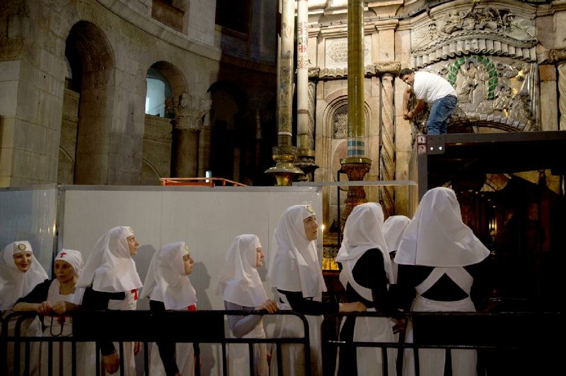 Christian nuns watch as a team of experts begin renovation of Jesus’ tomb in the Church of the Holy Sepulchre in Jerusalem’s old city, where Christians believe Jesus was buried, overcoming longstanding religious rivalries to carry out the first repairs at the site in more than 200 years.