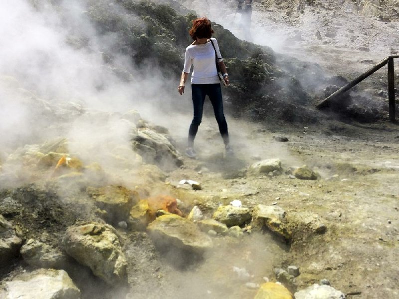 A woman takes a close look at a steaming fumarole at the Solfatara Crater bed near Naples, Italy. 