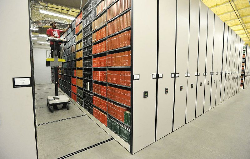 Kelvin Summerville, a library support technician, pulls books from a shelf Tuesday at the University of Arkansas at Fayetteville’s Library Storage Annex.