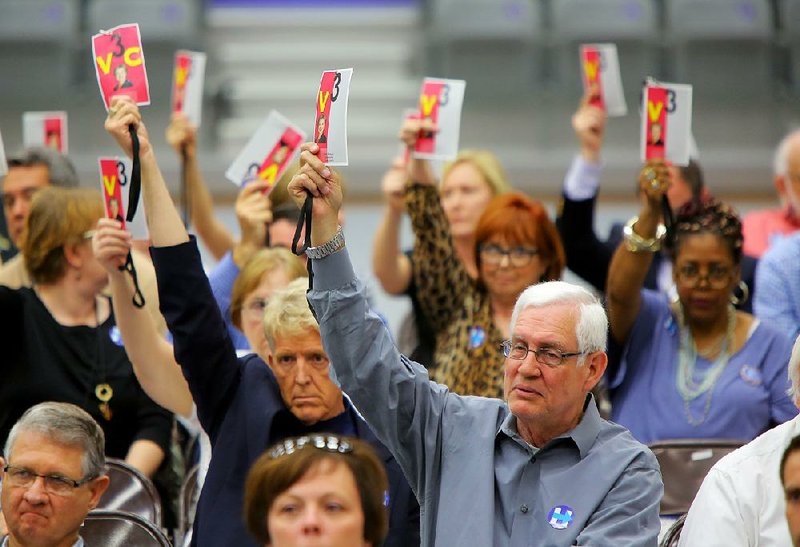 During a presidential nominating convention in Conway, supporters of Hillary Clinton raise their ID tags Saturday to vote for a delegate to the Democratic National Convention in Philadelphia.