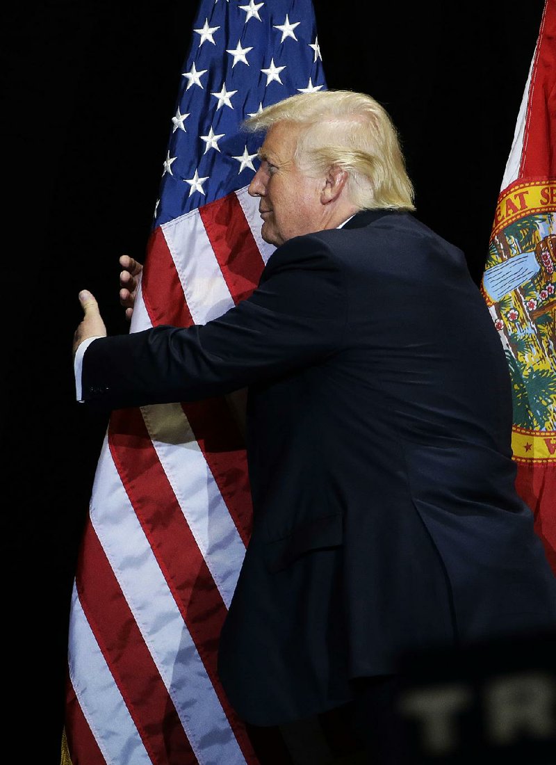 Donald Trump pauses during a speech Saturday in Tampa, Fla., to hug a flag. 