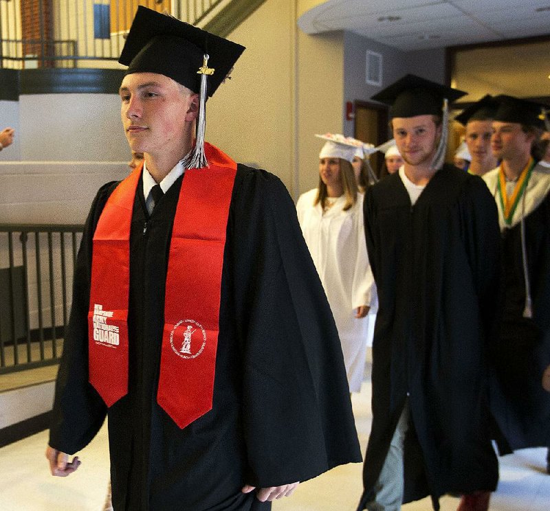 Michael Joy (left) wears his Army National Guard sash, and his National Guard uniform under his gown, as he marches with fellow Prospect Mountain High School graduates in their June 3 commencement in Alton, N.H. 
