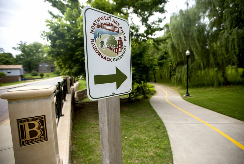 NWA Democrat-Gazette/JASON IVESTER Signs are posted Wednesday along the Northwest Arkansas Razorback Greenway in downtown Bentonville.