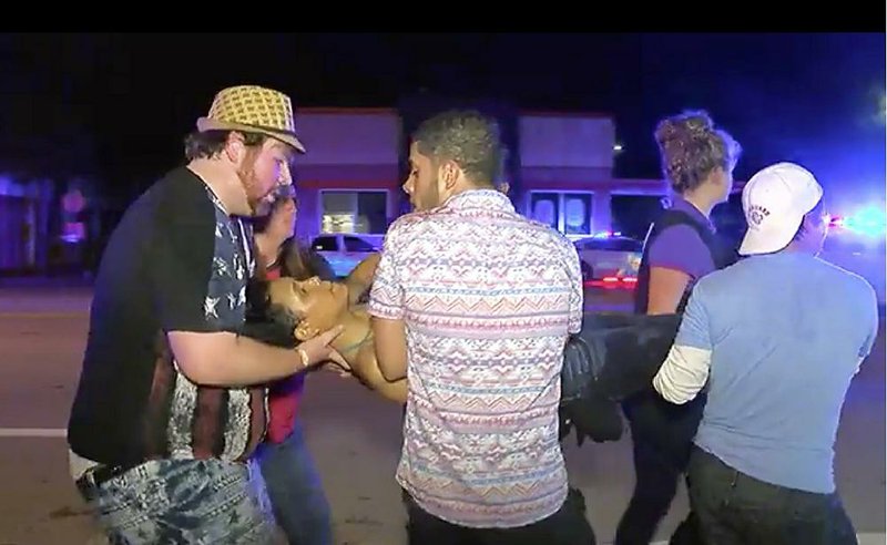 An injured person is carried out of Pulse nightclub in Orlando, Fla., early Sunday after a mass shooting.