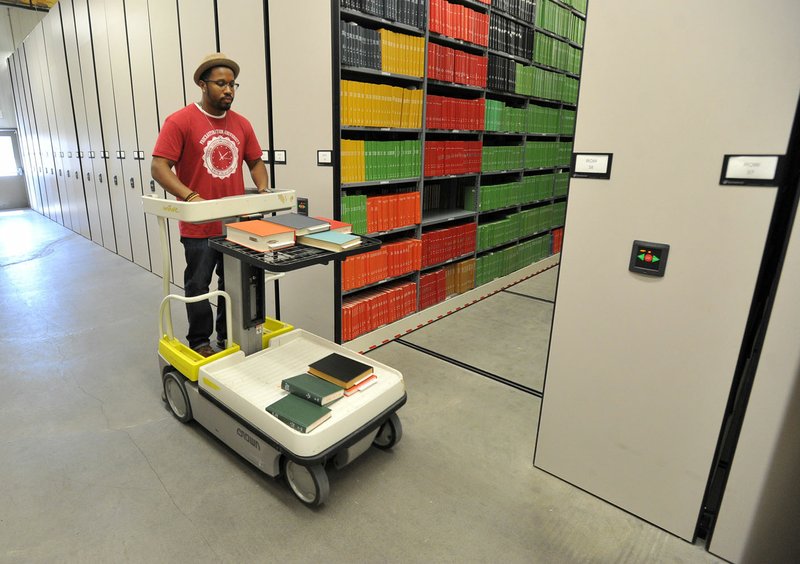 Kelvin Summerville, library support technician, pulls books from the shelves Tuesday at the Library Annex Storage Building on University of Arkansas campus in Fayetteville.