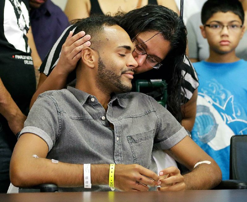Shooting victim Angel Colon gets a kiss from his sister Tuesday at Orlando Regional Medical Center in Florida. As nightclub attacker Omar Mateen kept firing, “I’m thinking, ‘I’m next, I’m dead,’” Colon said.