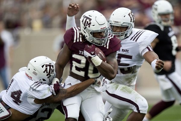 Texas A&M Myles Garrett (15) bears down on running back James White (20) while defensive back Justin Evans (14) gets a hand in during a spring NCAA college football game Saturday, April 9, 2016, at Kyle Field in College Station, Texas. (Timothy Hurst/College Station Eagle via AP)