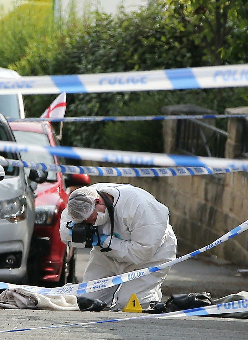 A forensics officer takes photos of a shoe Thursday at the scene where British Parliament member Jo Cox was fatally shot and stabbed in an attack in her constituency in Birstall, West Yorkshire. 