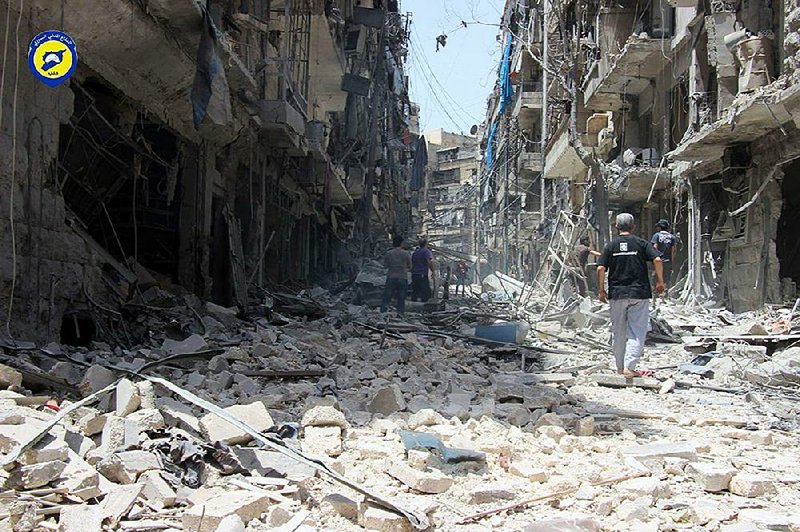 Syrians walk between buildings damaged by warplanes in Aleppo, Syria earlier this month. 