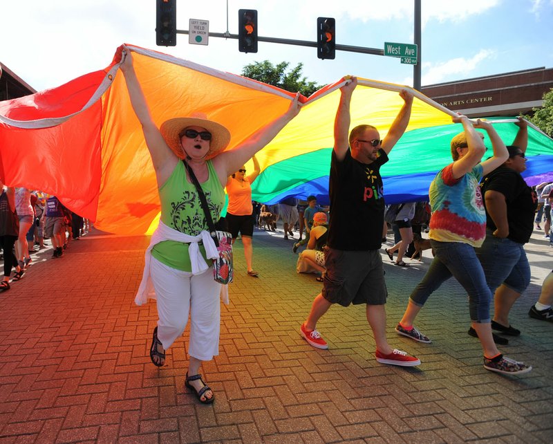 Participants walk the NWA Pride Parade on June 27, 2015, while carrying a large rainbow flag on Dickson Street in Fayetteville.